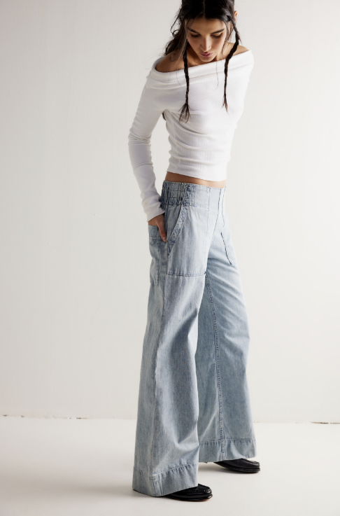 Woman wearing a white top and light blue jeans on a plain background
