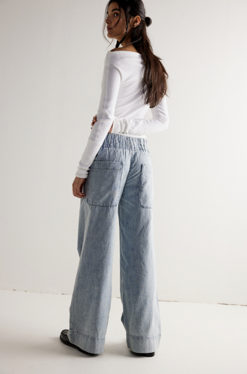 Woman wearing a white top and light blue pants on a white background