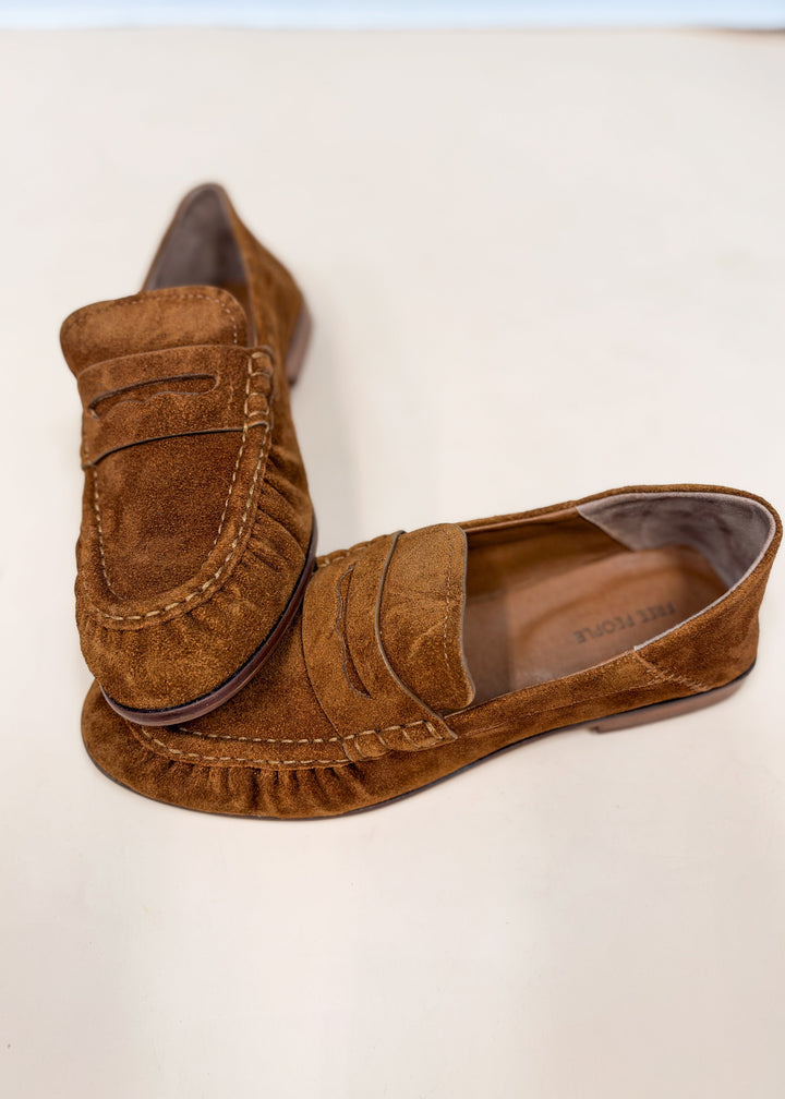 Pair of brown suede loafers on plain background