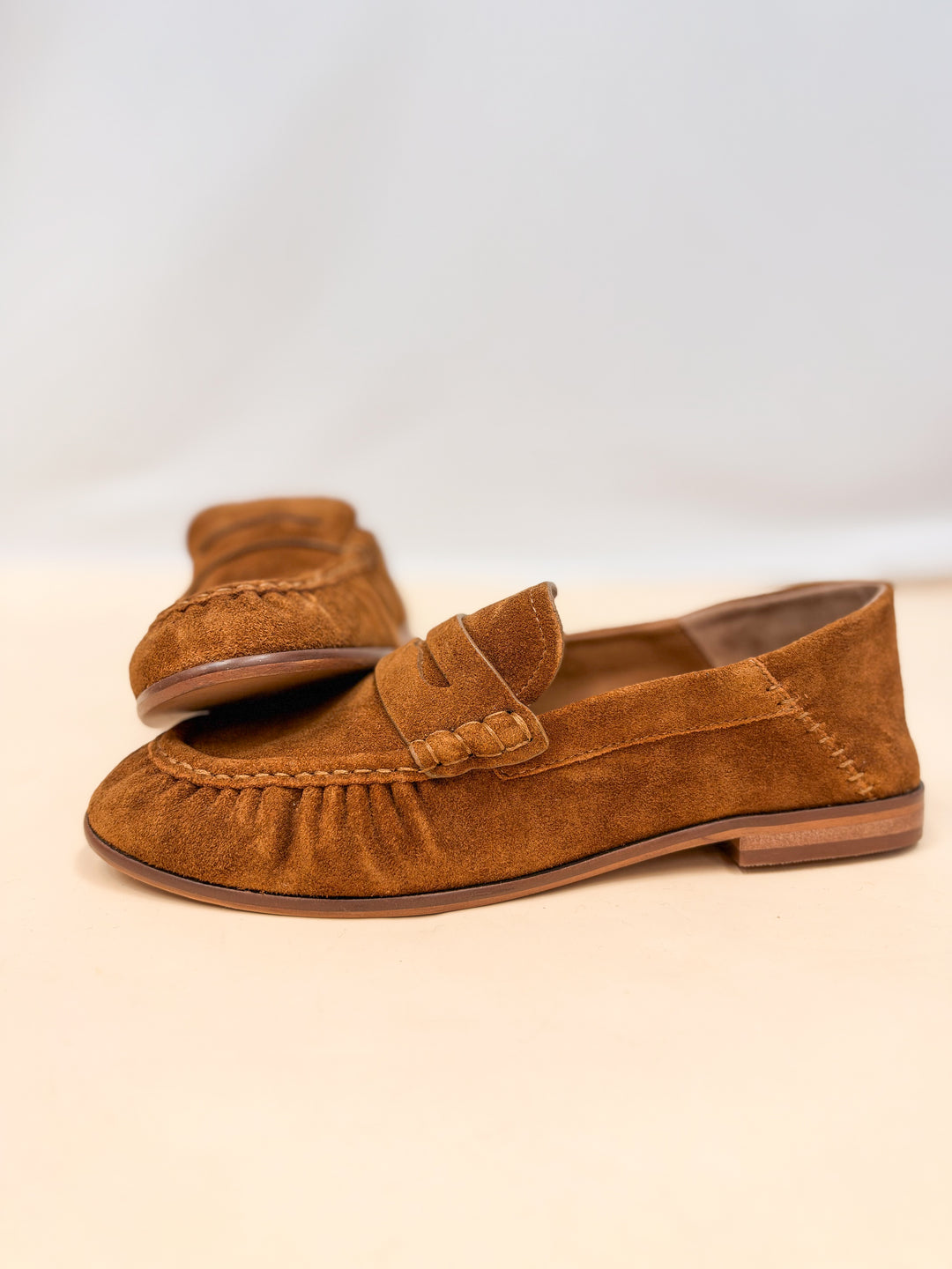 Pair of brown suede loafers on plain background