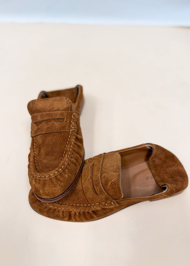 Pair of brown suede loafers on plain background