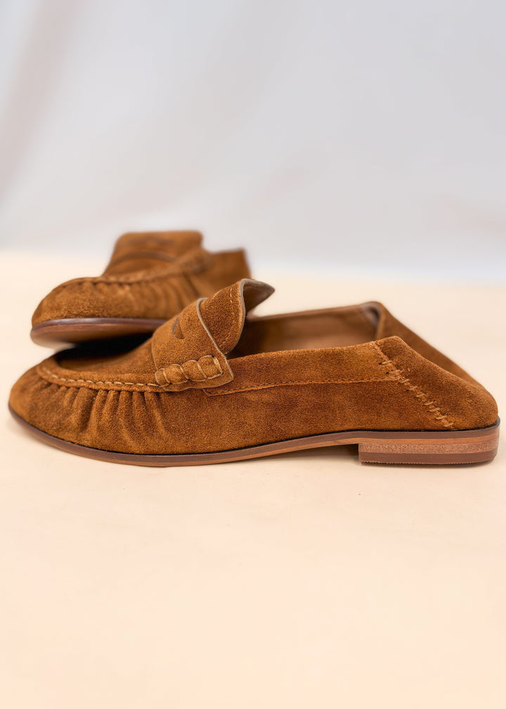 Pair of brown suede loafers on plain background