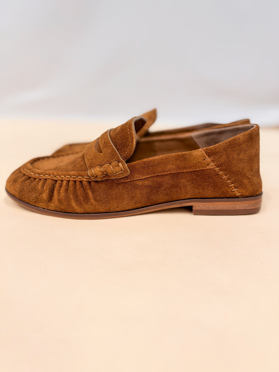 Pair of brown suede loafers on plain background
