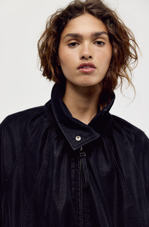 Close up of woman wearing black suede jacket on plain background