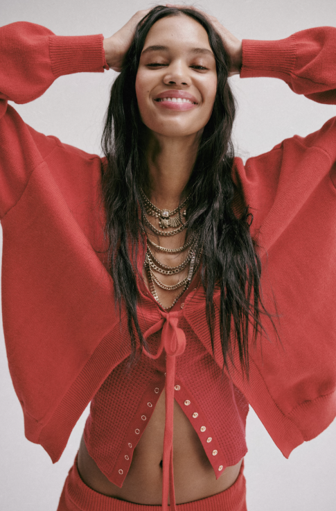 Woman wearing two red cardigans with red pants on plain background