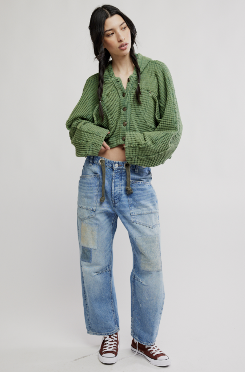 Woman wearing green cardigan and denim jeans on white background