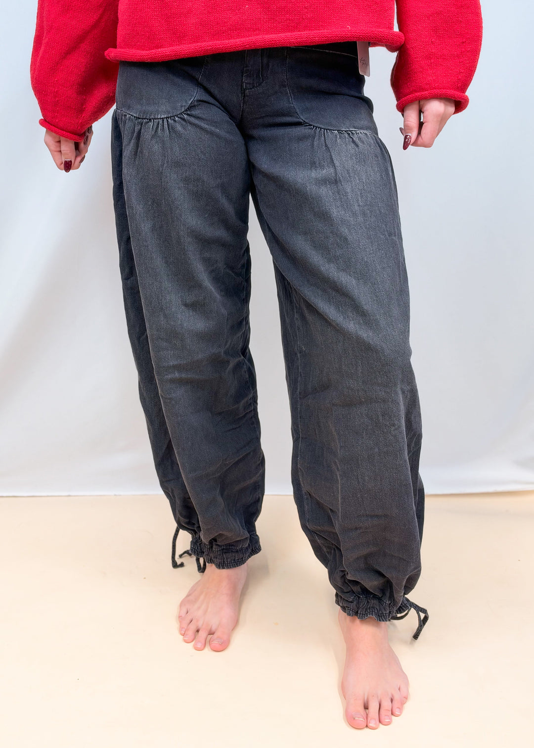 Woman shown waist down wearing black balloon pants on plain background