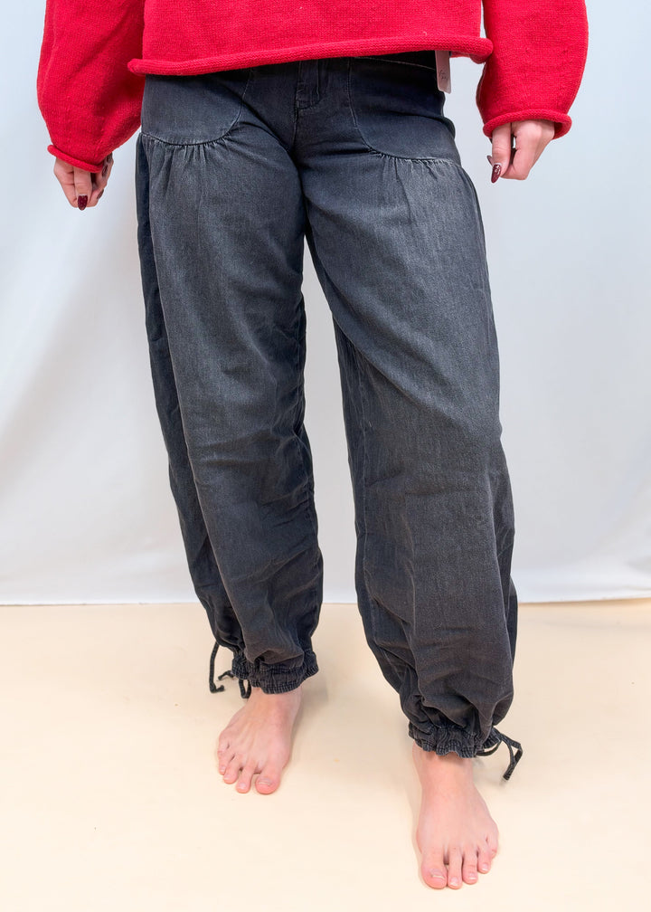 Woman shown waist down wearing black balloon pants on plain background