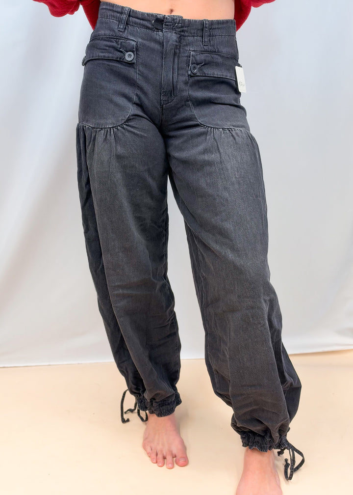 Woman shown waist down wearing black balloon pants with front pocket detail on plain background