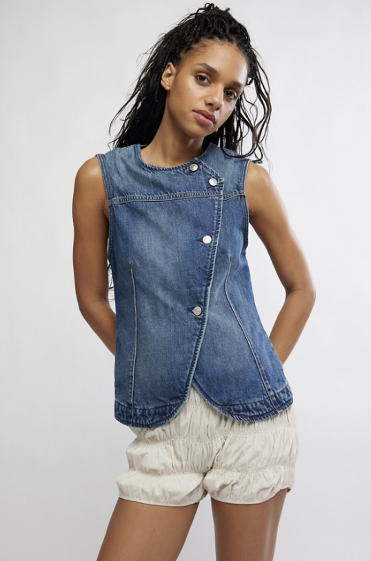 Woman wearing denim top and white shorts on plain background