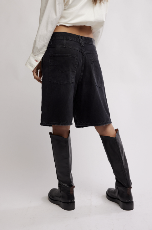 Person wearing black knee-high boots and black cargo shorts on a white background
