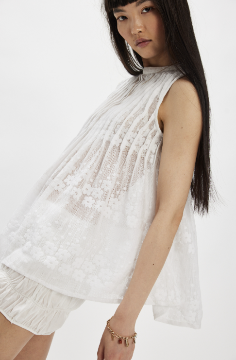 Woman wearing white mesh top and shorts on plain background