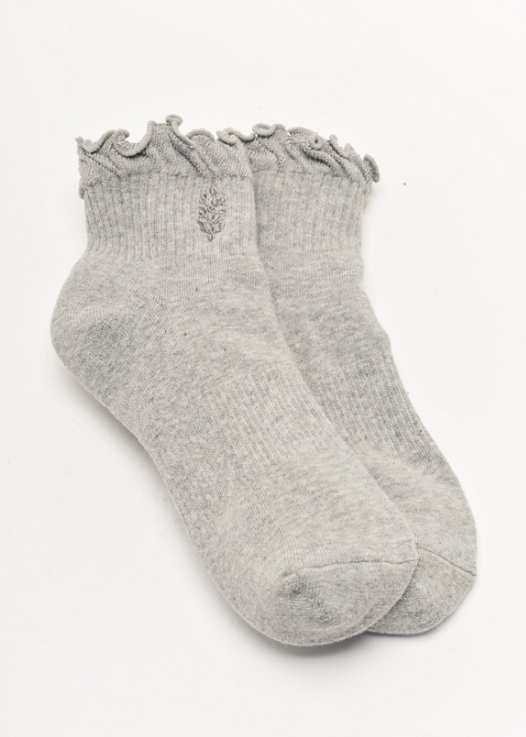 Pair of grey ankle length ruffle socks on plain background with free people movement logo on front