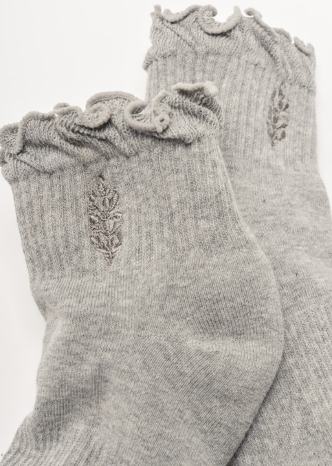 Pair of grey ankle length ruffle socks with free people movement logo on plain background