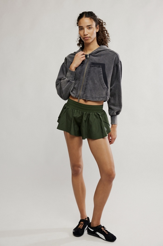Woman wearing green shorts and grey hoodie on white background