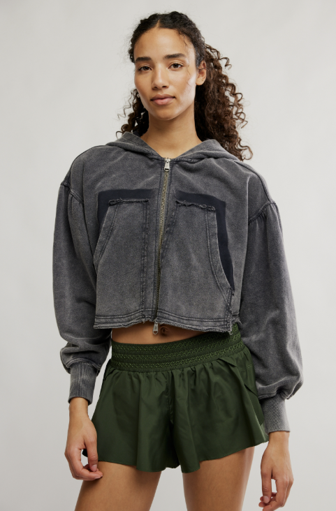 Woman wearing green shorts and grey hoodie on white background