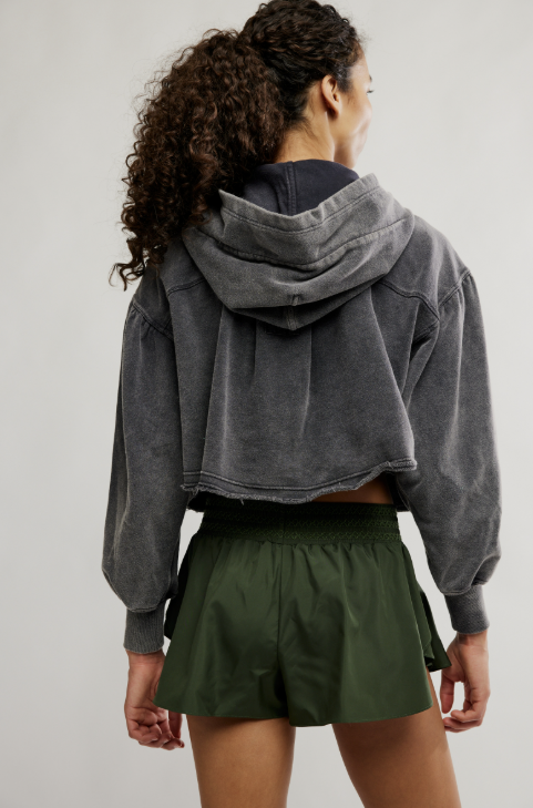 Woman wearing green shorts and grey hoodie on white background