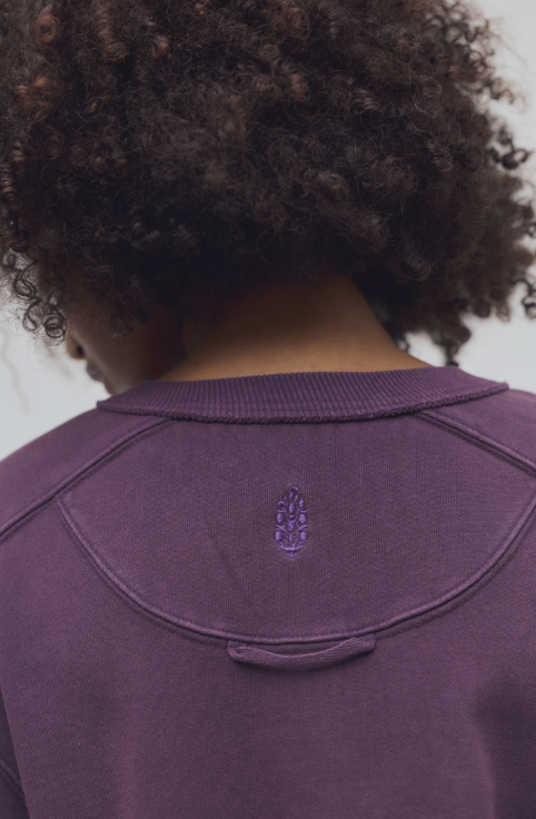 Close up of logo on purple sweatshirt on plain background
