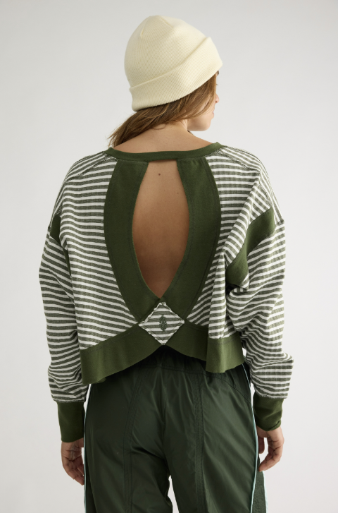Woman shown from back wearing green and white stripe top, green pants and ivory beanie on plain background