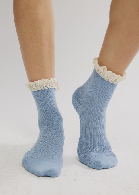 Person wearing blue ankle length ruffle socks on plain background