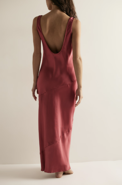 Back of woman wearing a red satin dress on plain background