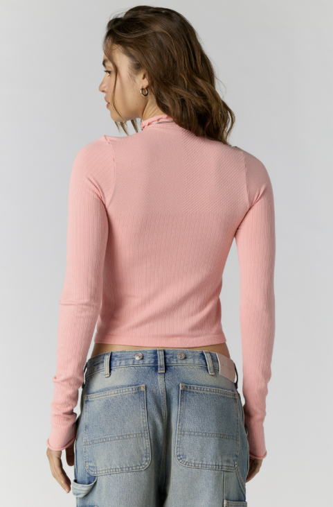 Woman shown from back wearing pink body fitting mock neck with jeans on plain background