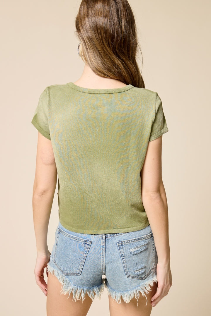 Back of woman wearing green tshirt and denim shorts on plain background
