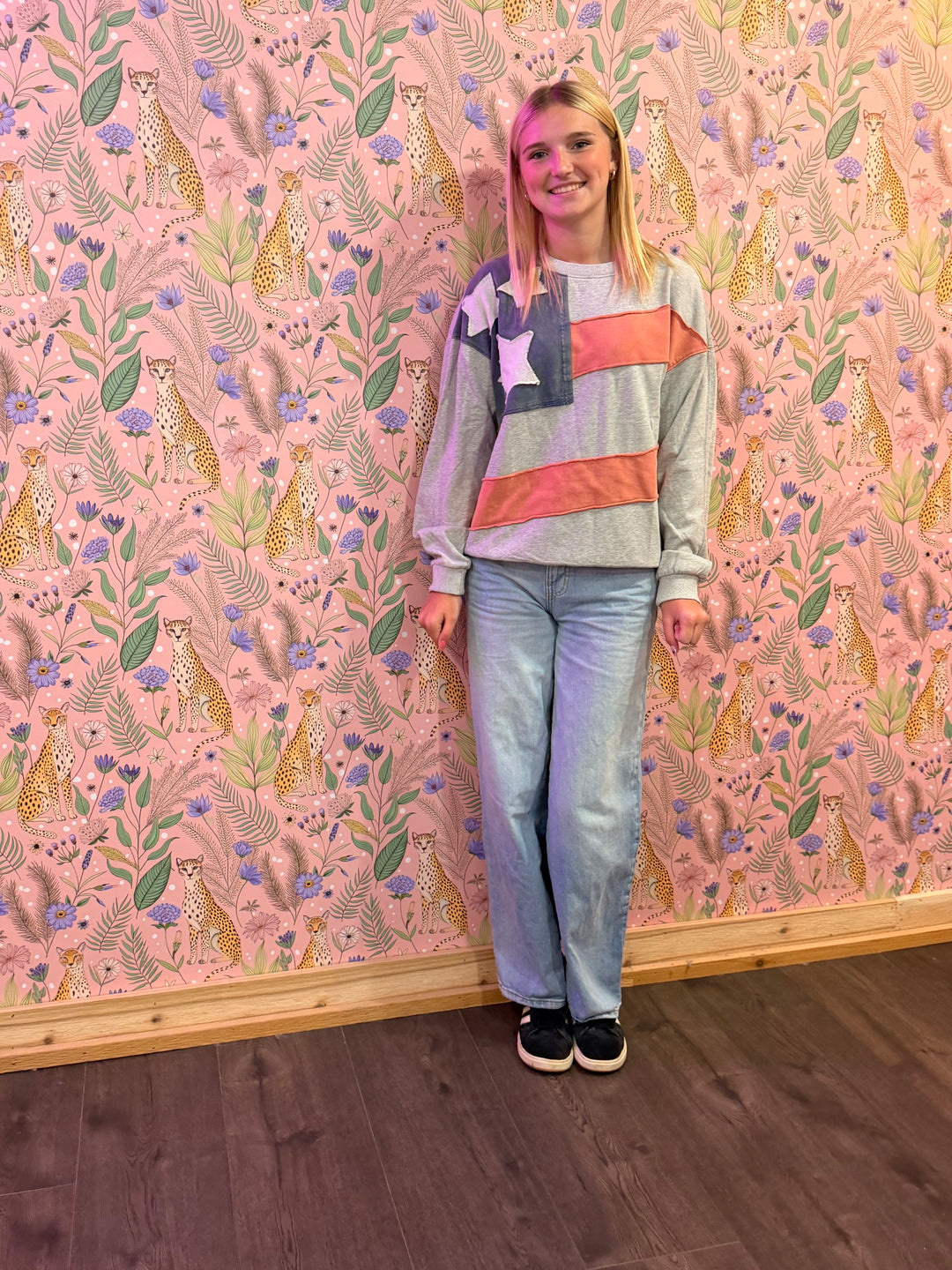 Person standing in front of a wall with a colorful animal pattern