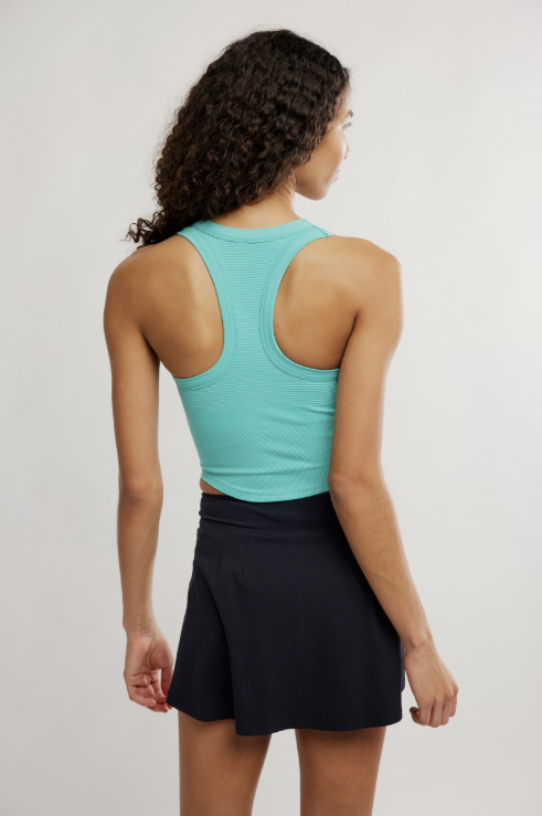 Person wearing a turquoise tank top and black skirt on a plain background