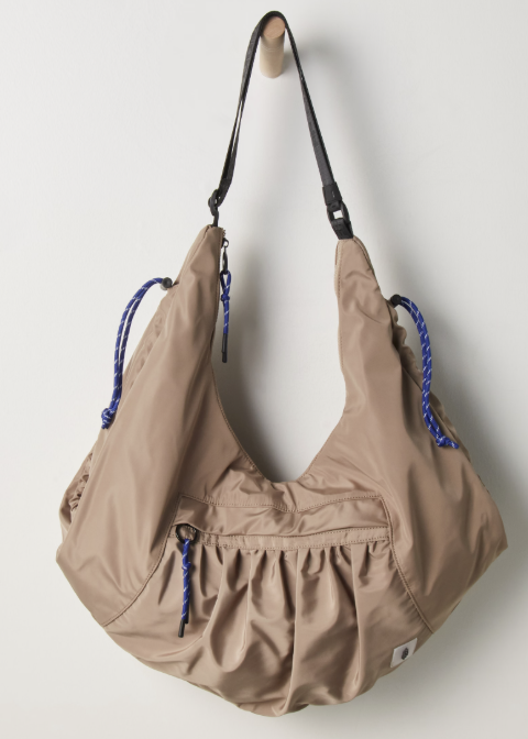 Beige tote bag hanging on wooden peg on plain wall