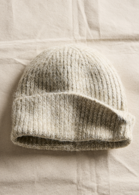 Knitted beanie on a textured beige surface