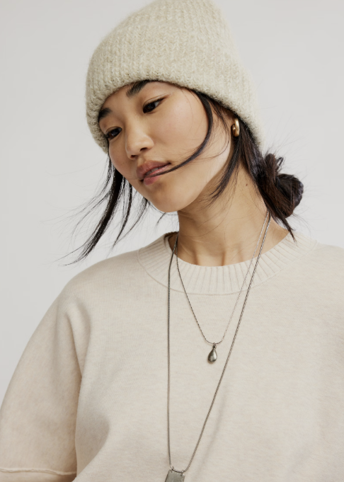 Woman wearing beige knitted beanie and beige sweater on plain background