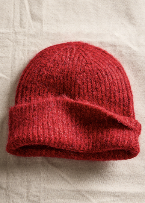 Red chunky knit beanie on textured beige background