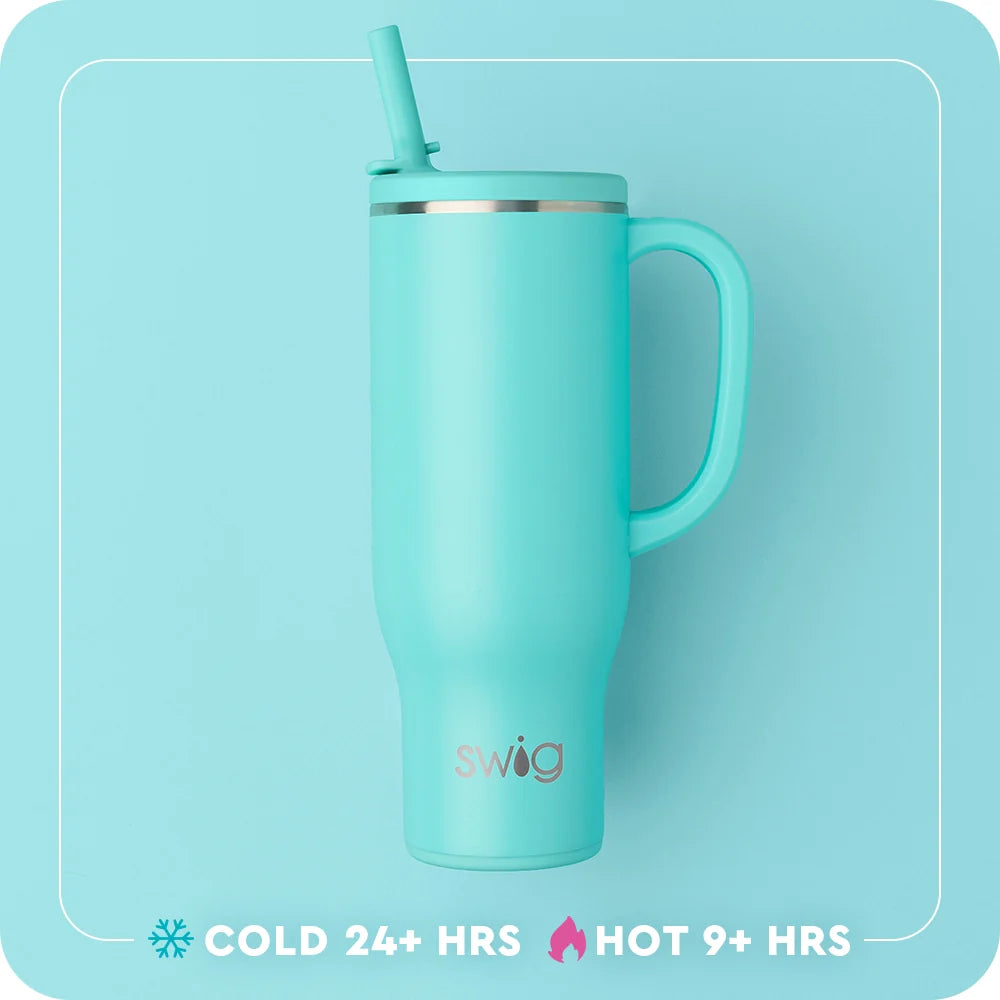 A mint green Swig vacuum-insulated travel tumbler with a matching handle and straw lid, shown against a matching light blue background with product feature text at the bottom.
