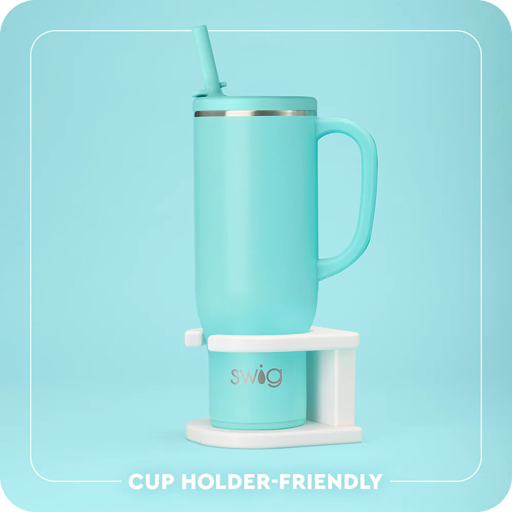 Turquoise mug with handle and straw on a white stand against a light blue background