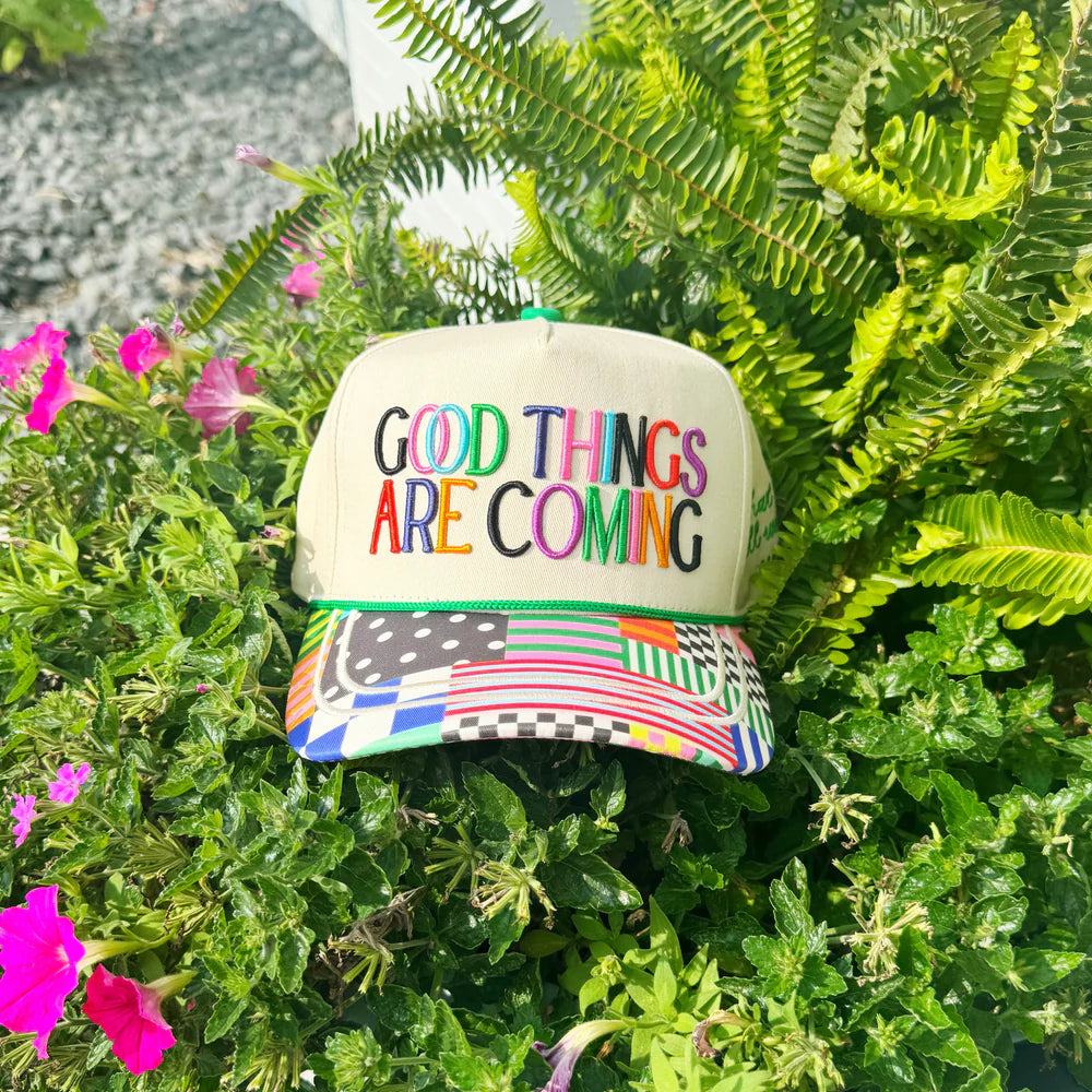 Cap with 'Good Things Are Coming' text on a green plant background