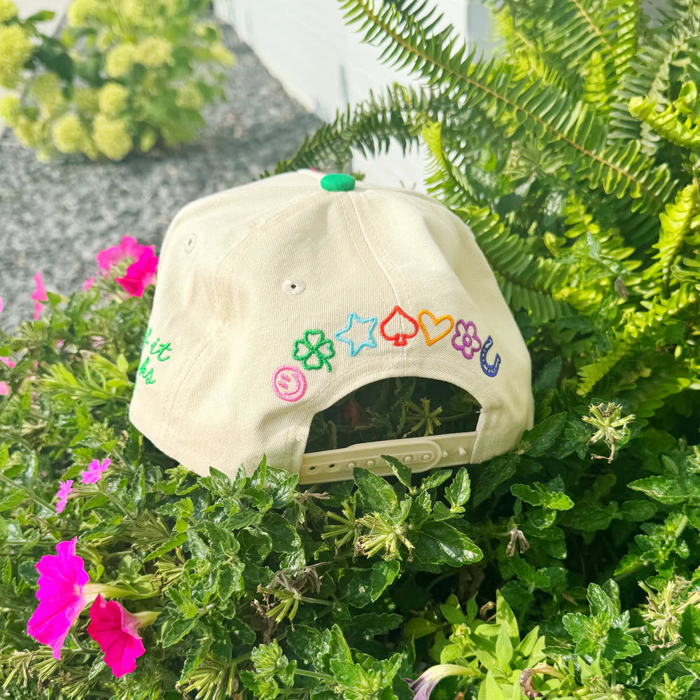 Beige cap with colorful symbols on a green plant background