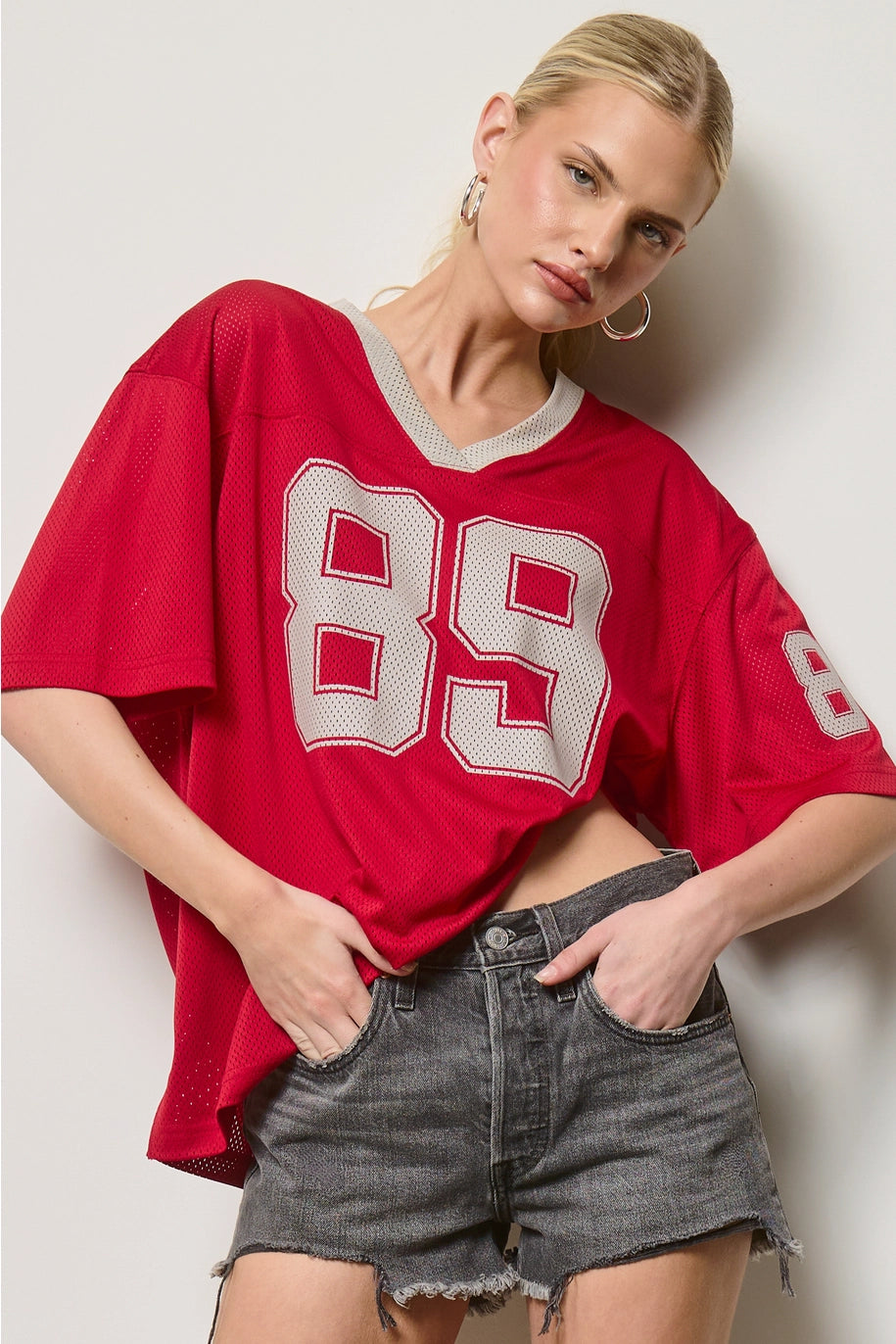 Person wearing a red sports jersey with the number 89 on a plain background