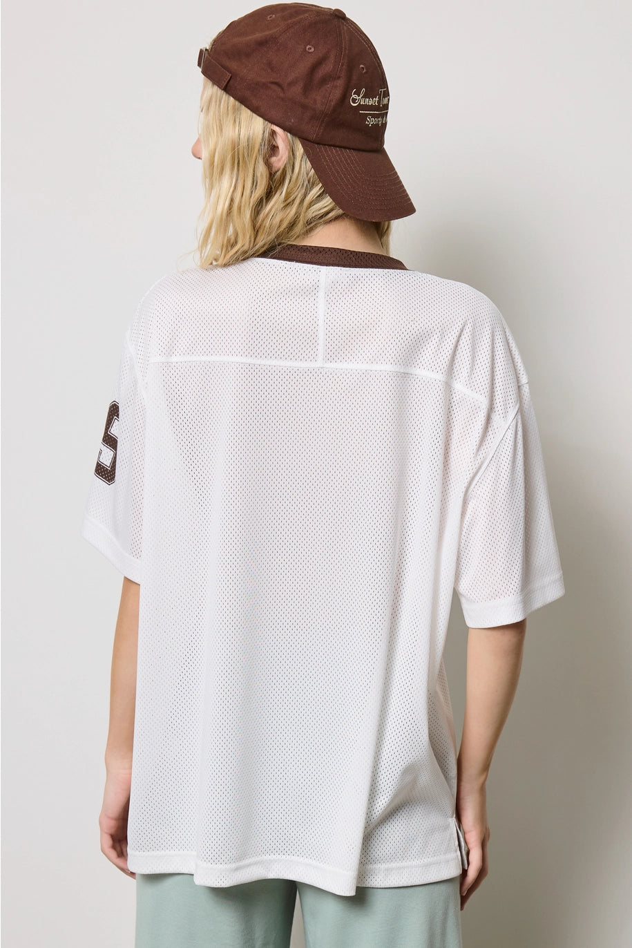 Back of woman wearing white jersey on plain background