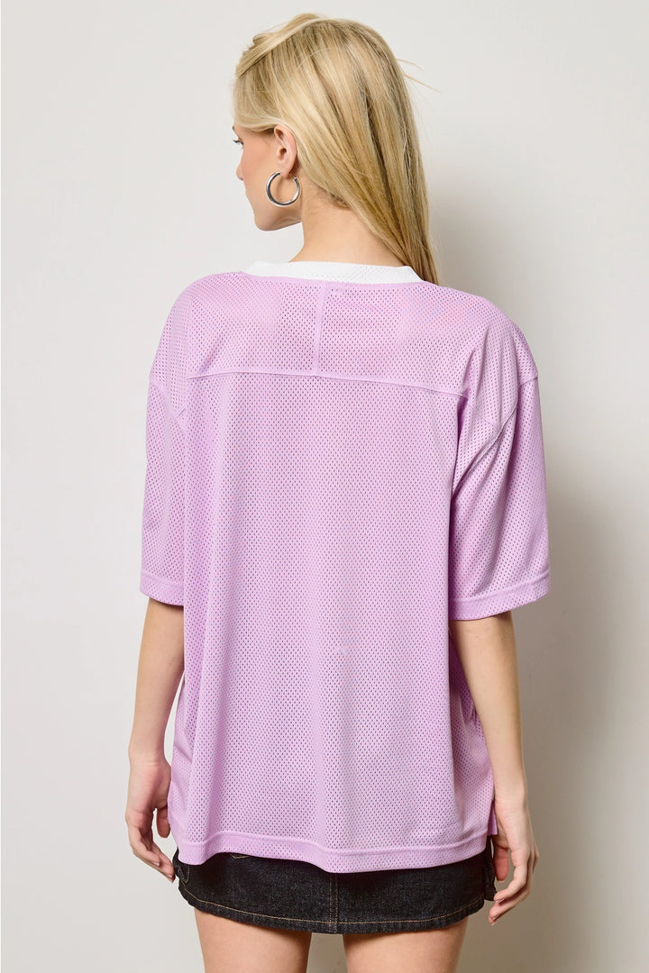 Person wearing a purple mesh top with a plain background