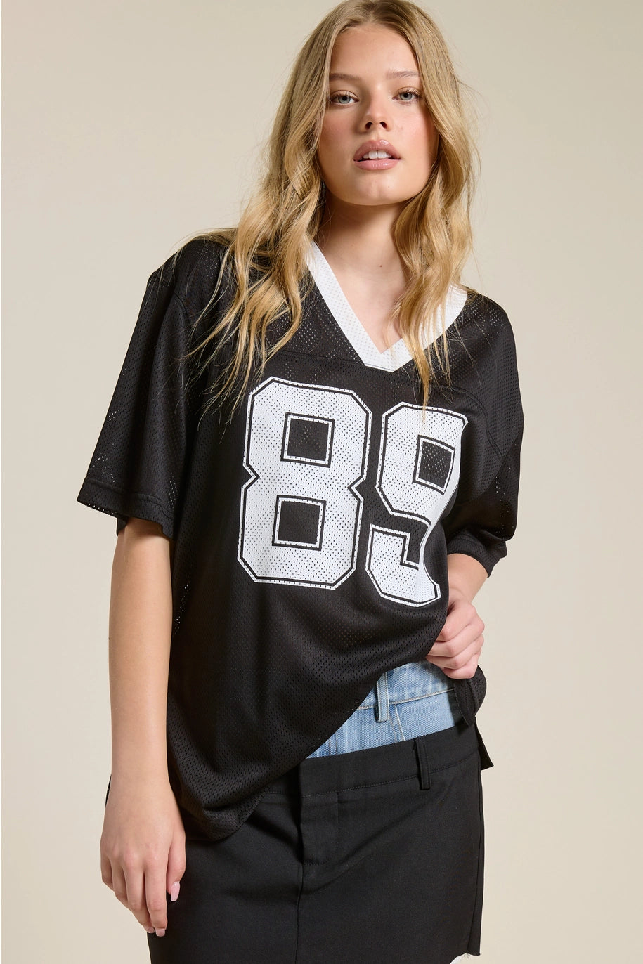 Woman wearing a black jersey with the number 89 on a beige background