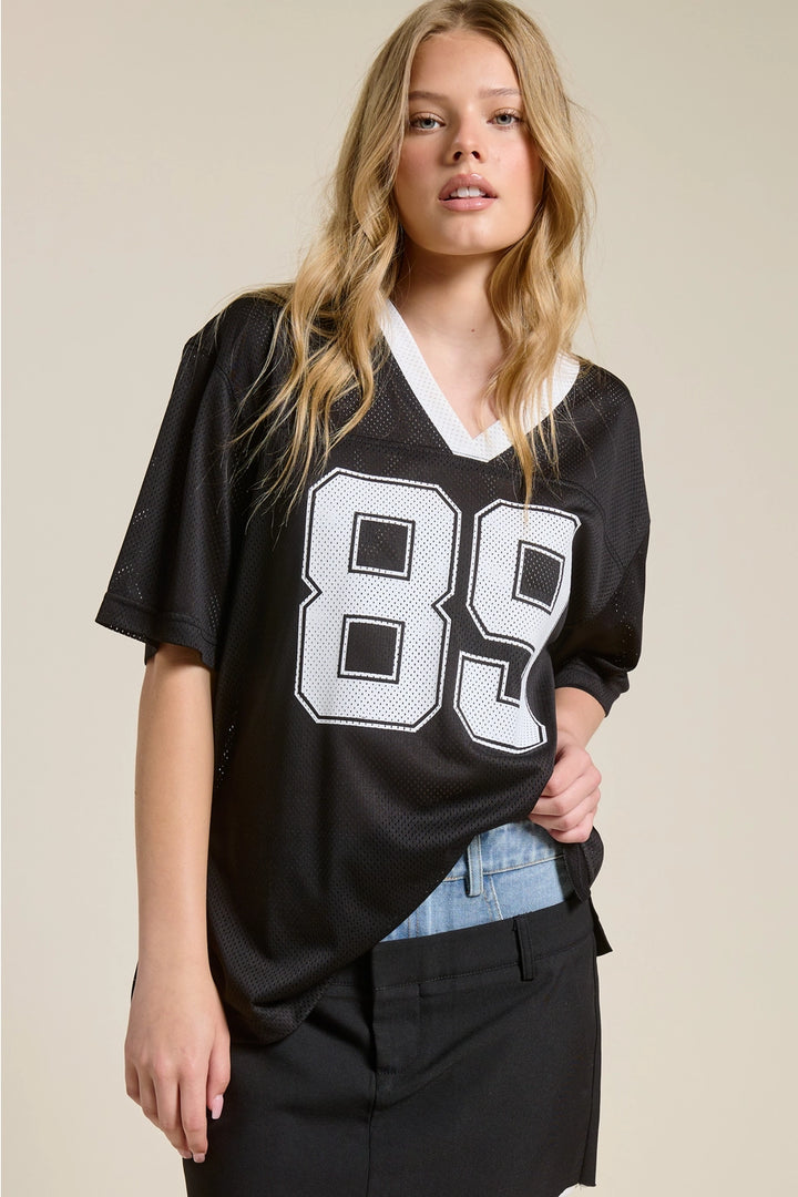Woman wearing a black jersey with the number 89 on a beige background