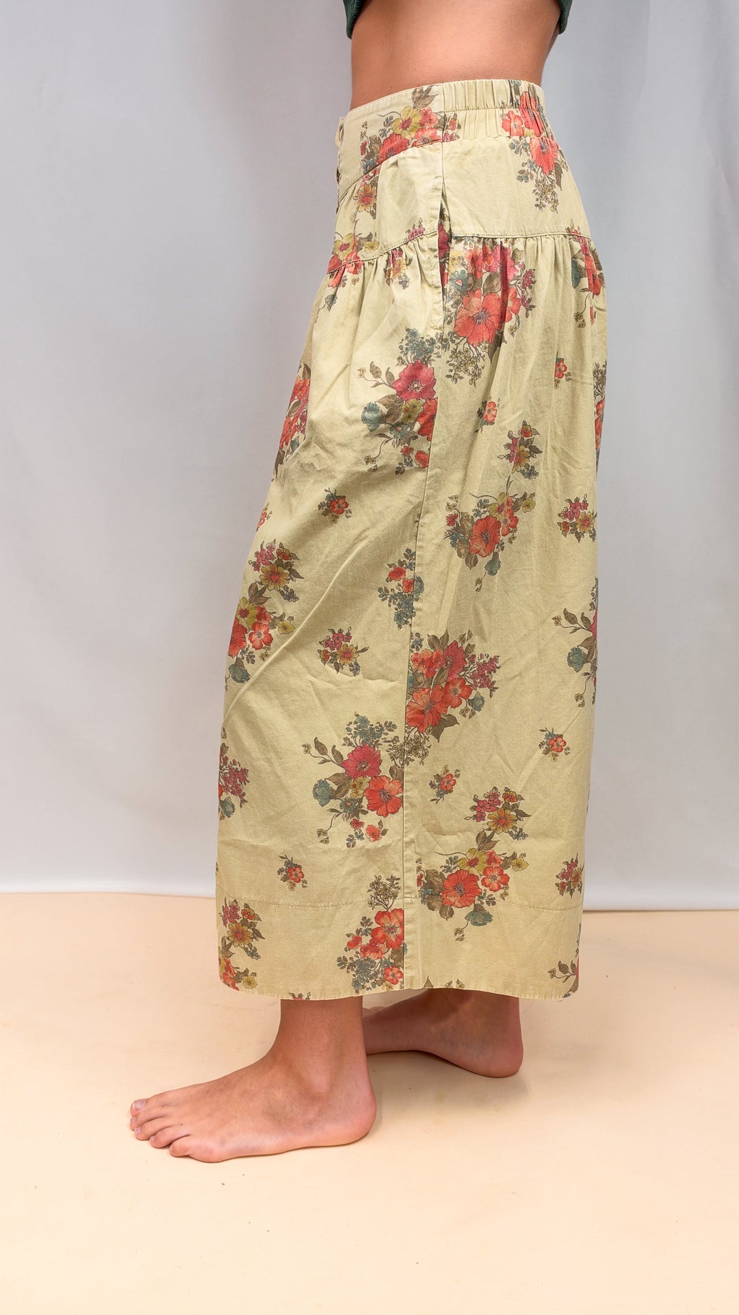 Woman shown from side view wearing floral pants on plain background