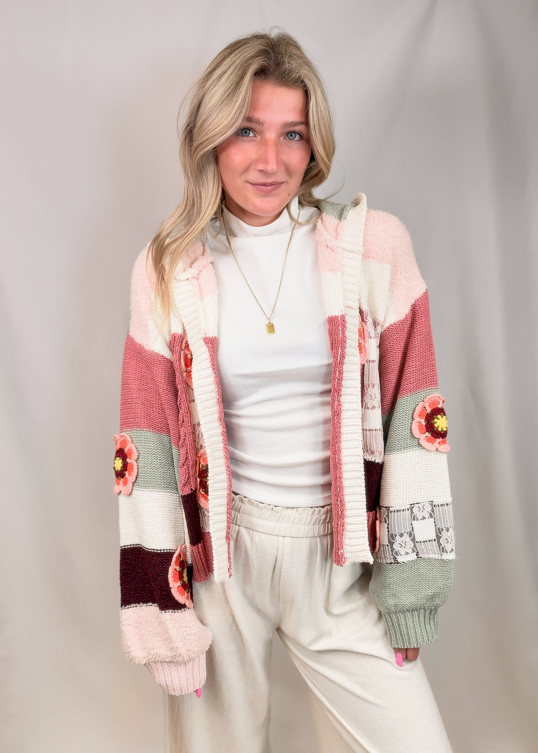 Woman wearing crochet knit cardigan with floral details on plain background