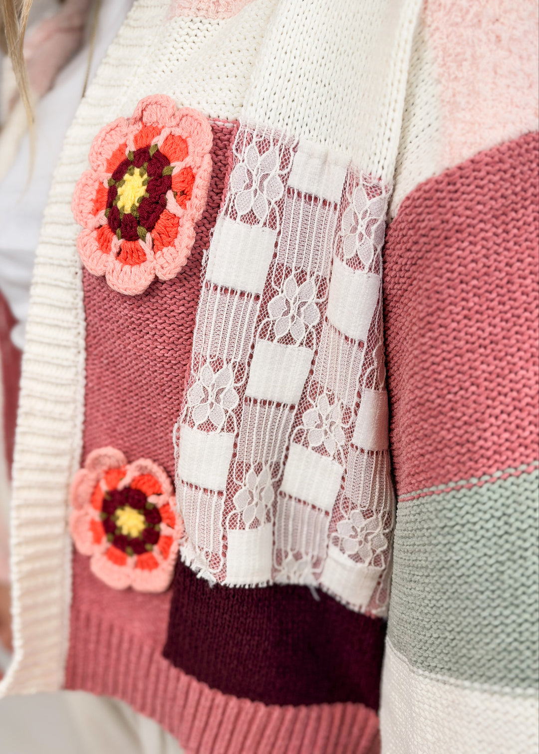 Close up of crochet knit cardigan with lace and floral details 