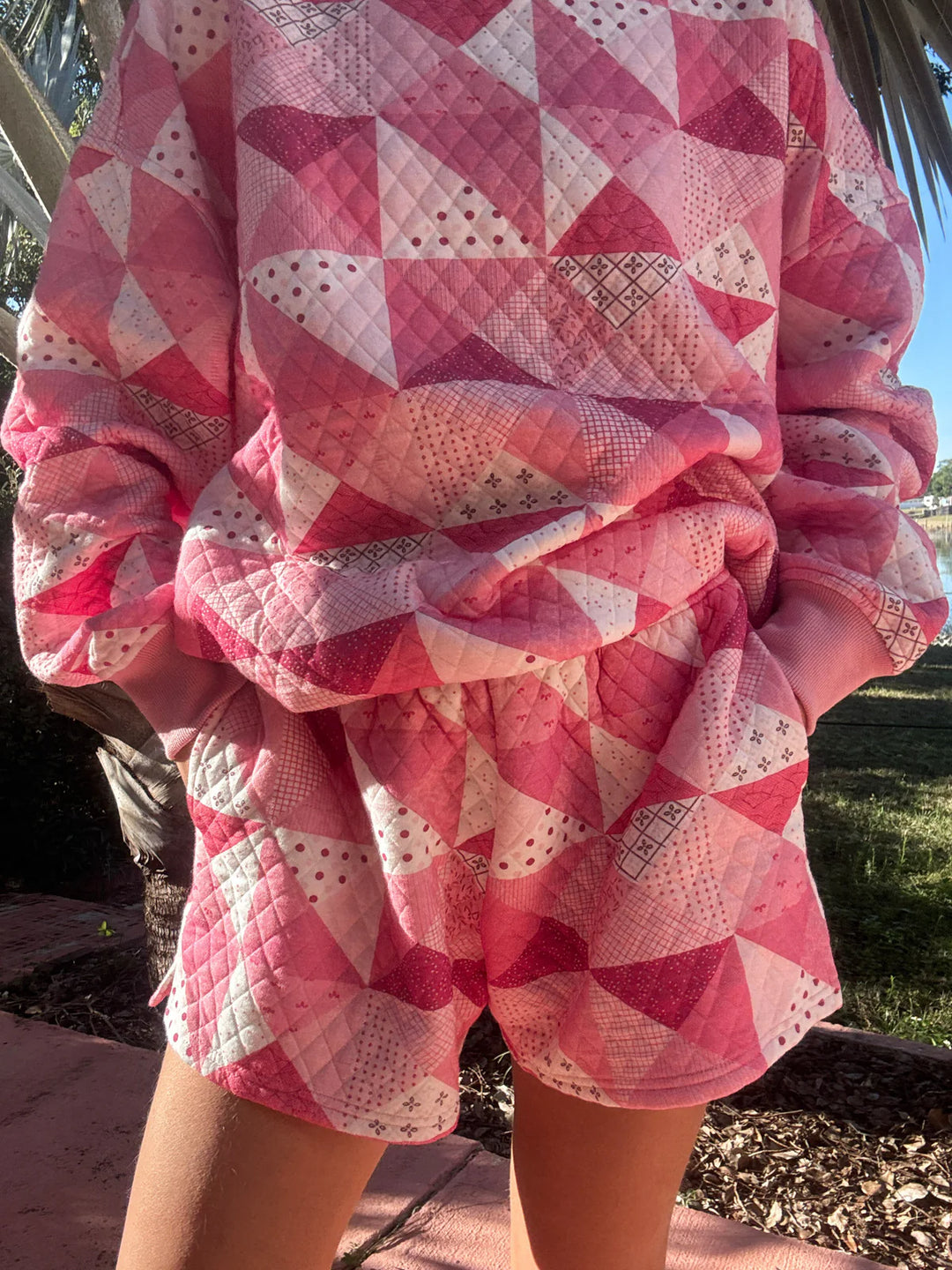 Person wearing pink quilted shorts and top standing outdoors