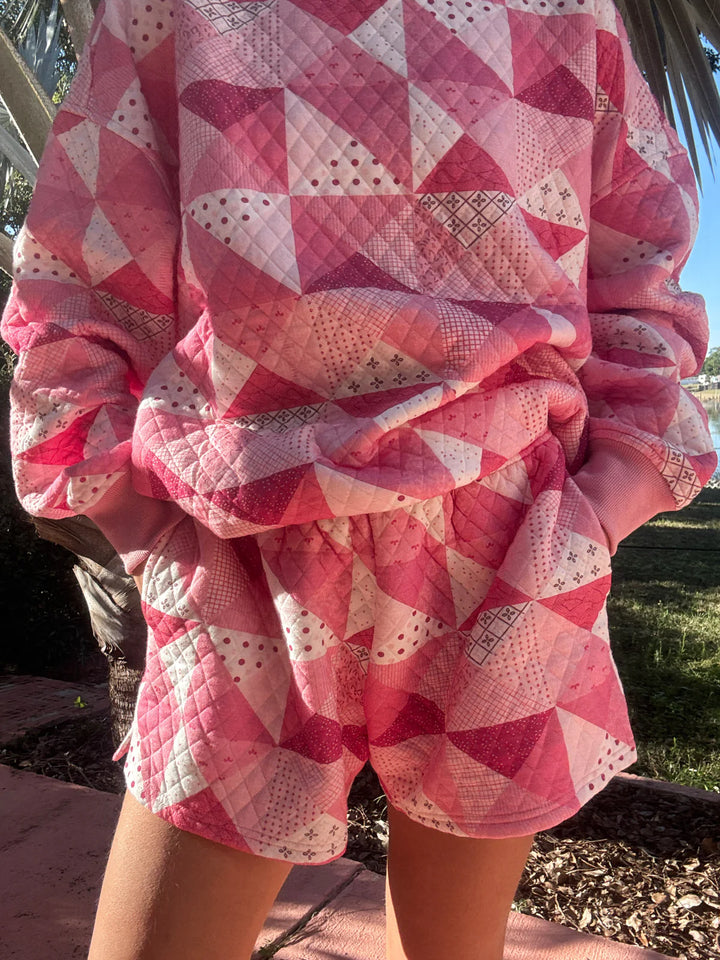 Person wearing pink quilted shorts and top standing outdoors