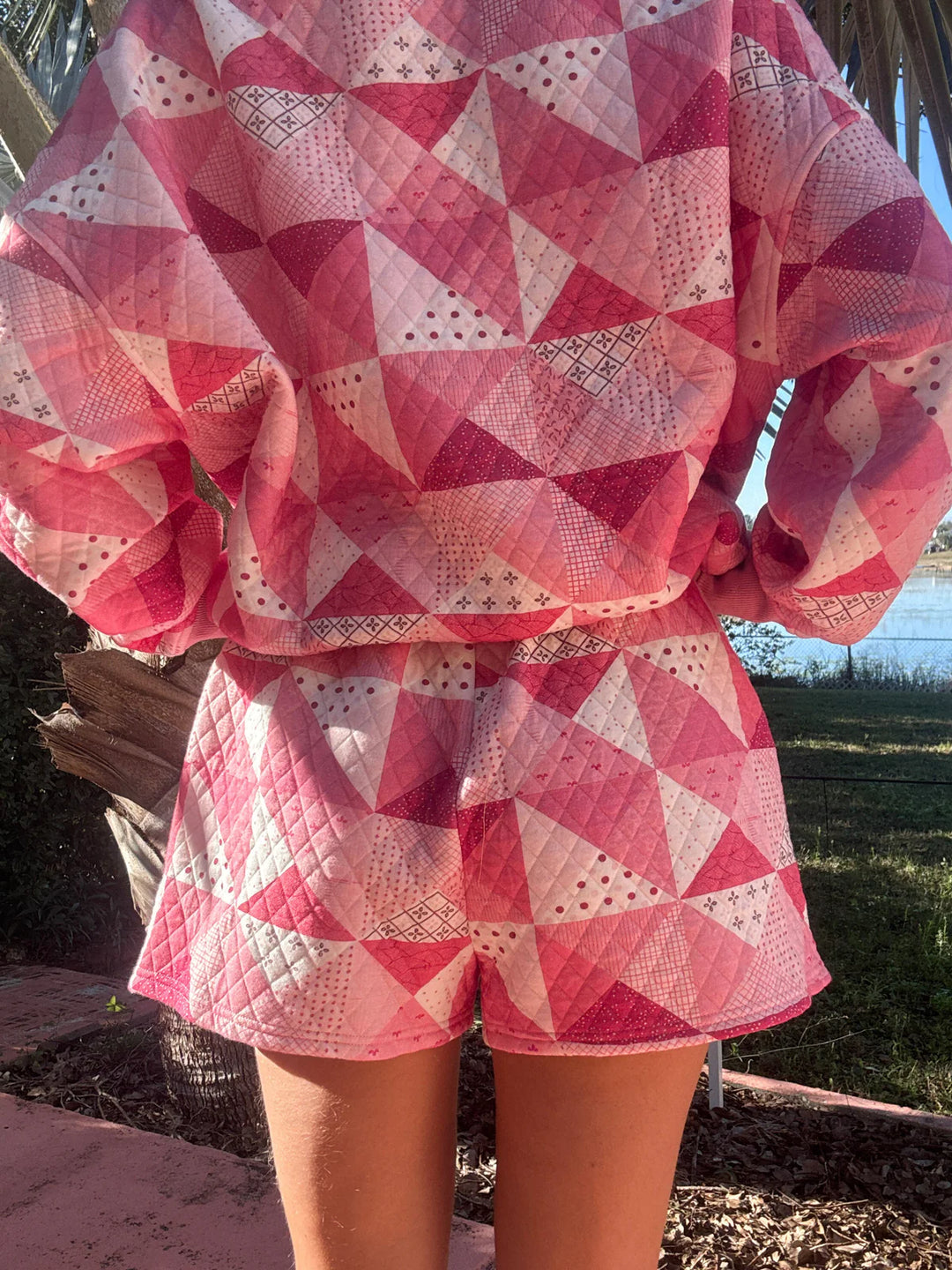 Back of person wearing pink quilted shorts and shirt standing outdoors