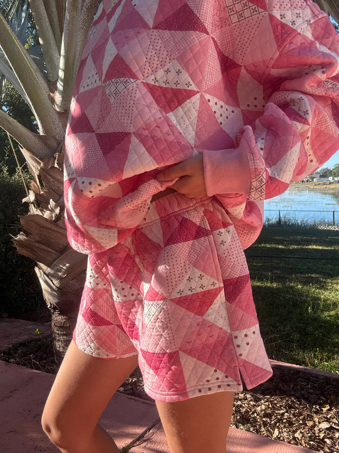 Person wearing pink quilted shorts and shirt standing outdoors