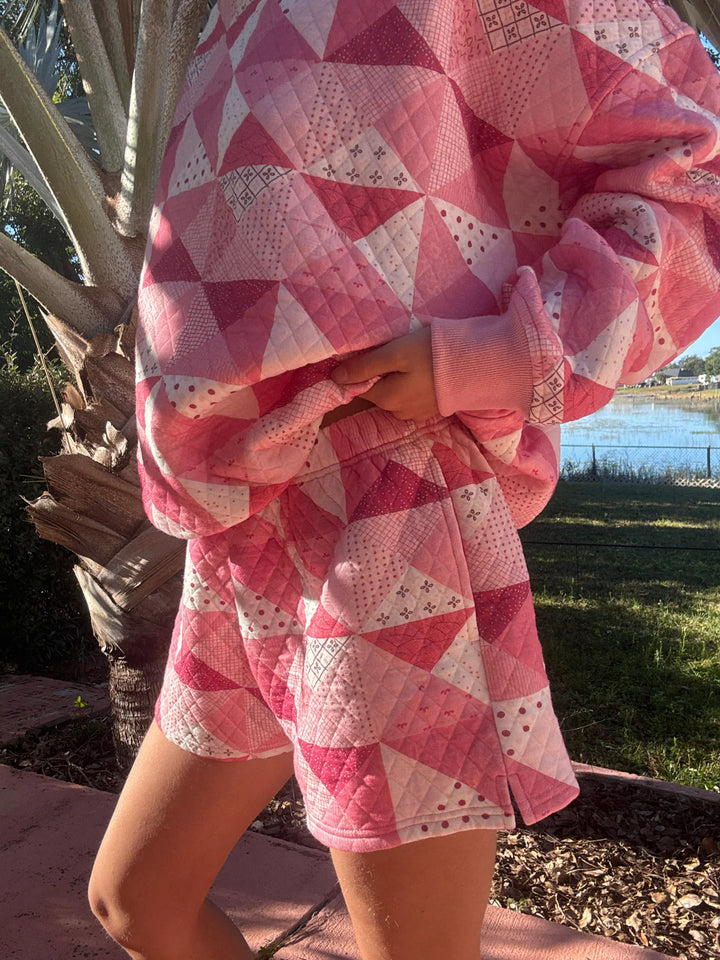 Person wearing pink quilted shorts and shirt standing outdoors